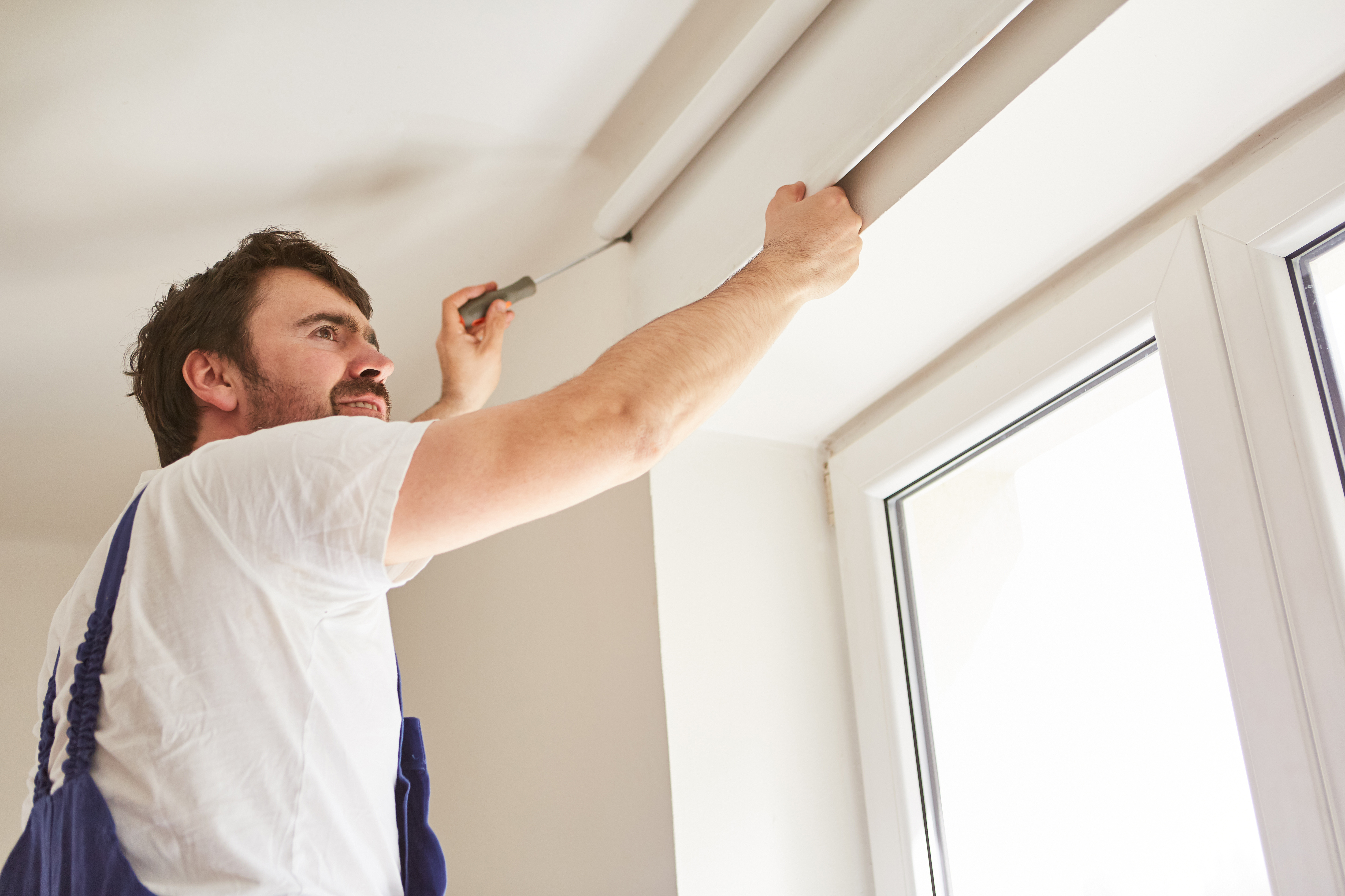 Une personne applique l'isolant sur un caisson de volet roulant intérieur.