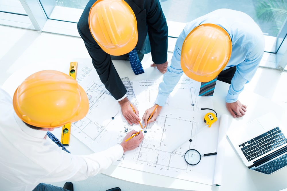 La rénovation énergétique d'une copropriété et son plan d'isolation extérieure sont au centre d'une discussion entre trois techniciens.